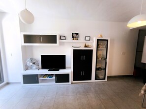 Un salon moderne doté d’un téléviseur à écran plat, d’étagères intégrées, d’un meuble et d’une vitrine.