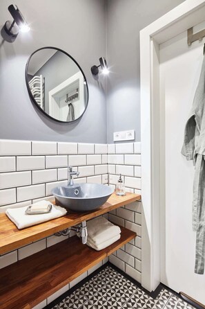 A bathroom with a round mirror, a vessel sink, and a wooden vanity.