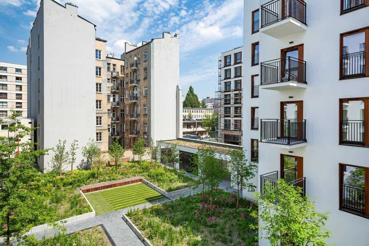 Et moderne boligkompleks med flere bygninger, altaner og en anlagt have.