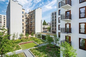 A modern apartment complex with multiple buildings, balconies, and a landscaped garden area.