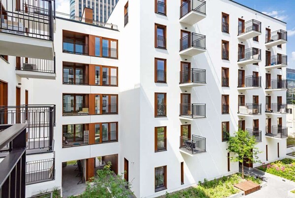 A modern multi-story residential building with balconies, large windows, and a flat roof.