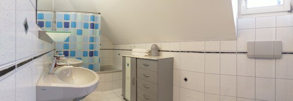 Ein Badezimmer mit Waschbecken, Spiegel, Toilette und einer blauen Duschkabine.