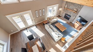 A spacious living area with a fireplace, a dining table, and a sofa. - Elevated Dog Friendly Escape w/ Hot Tub & Fire Pit (Oakland)