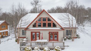 A two-story house with a snow-covered roof and a front porch with a railing. - Elevated Dog Friendly Escape w/ Hot Tub & Fire Pit (Oakland)