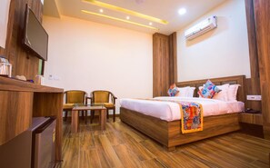 A hotel room with a wooden bed, a TV, a desk, and two chairs.