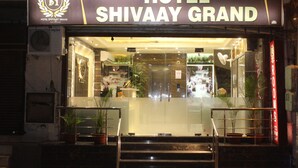The entrance of Hotel Shivaay Grand with a glass facade, steps leading up to the entrance, and potted plants at the base. - Shivaay Grand (Amritsar)