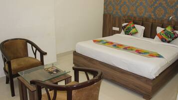 A bedroom with a wooden bed, two chairs, a glass table, and a patterned wall.