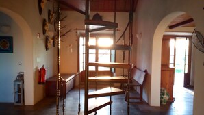 Un interno rustico con una scala in legno, una panca e una mensola a parete.