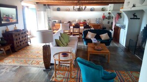 Un soggiorno spazioso con un divano, un tavolino e una poltrona blu. Sullo sfondo, una zona pranzo con tavolo e sedie.