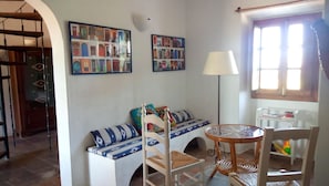 Uma sala de estar acolhedora com um sofá, uma poltrona, uma mesa e duas imagens penduradas na parede.