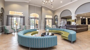 A spacious lobby with a curved seating area, a reception desk, and large windows allowing natural light.