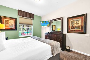 Ein Hotelzimmer mit Bett, Fernseher, Schminktisch und gerahmten Bildern an den Wänden.