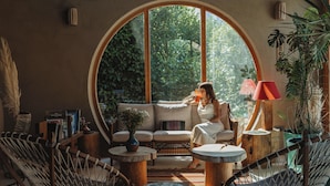 A cozy room with a large arched window, a sofa, and a coffee table. - Pachamama Alacati  (Cesme)