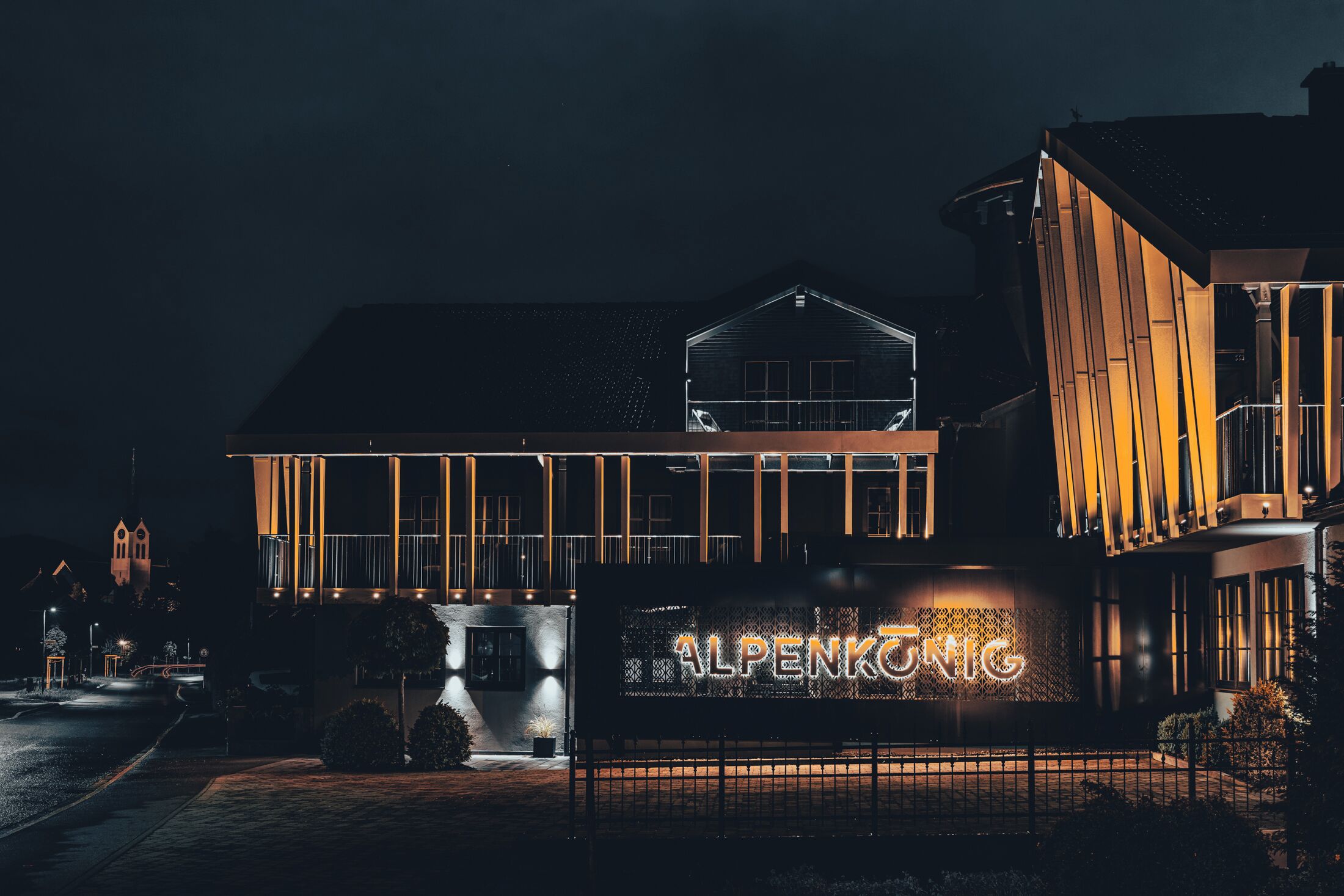 A modern building with a prominent illuminated sign reading "ALPENKÖNIG".