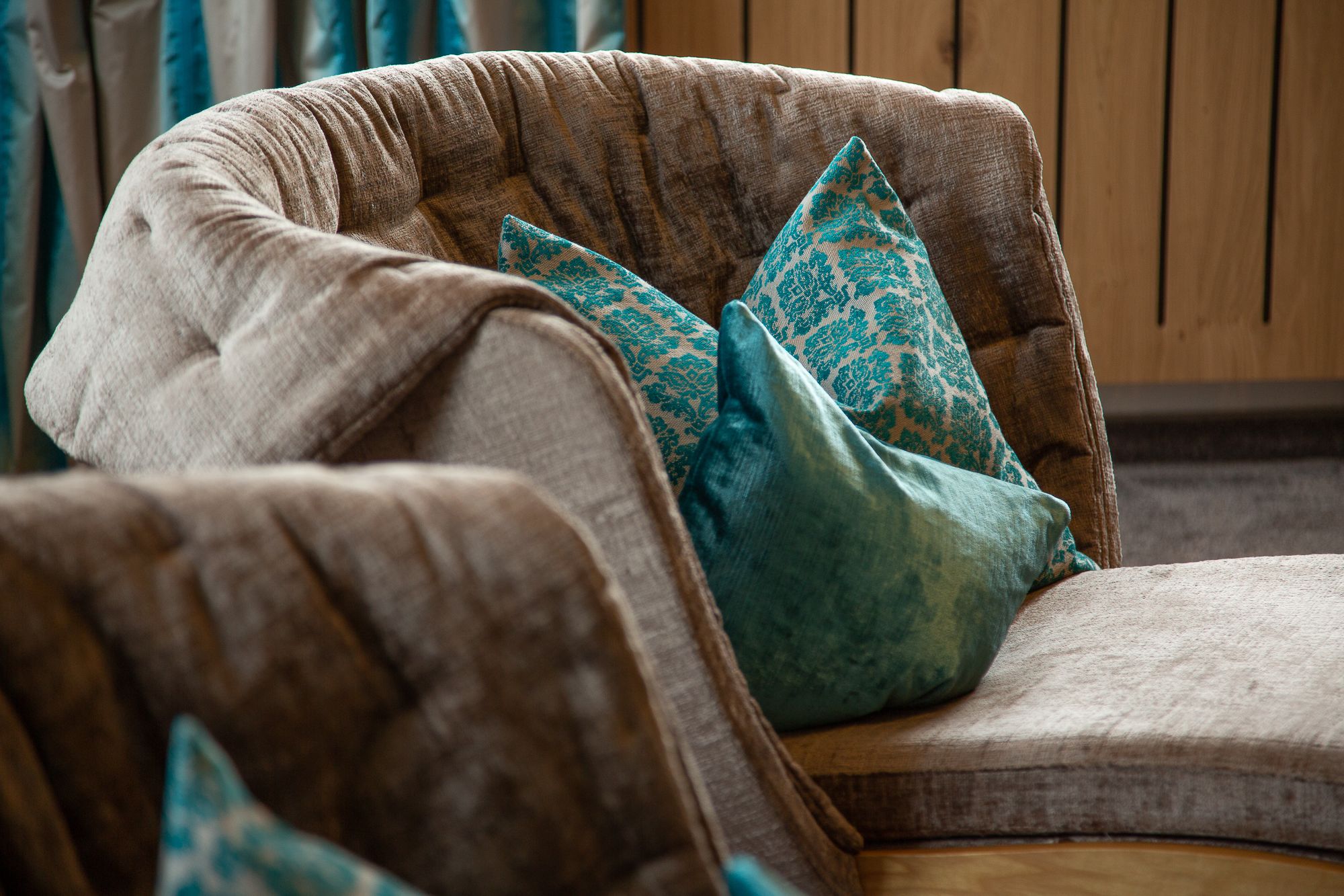 A brown upholstered armchair with a curved backrest and a cushion featuring a blue and white pattern.