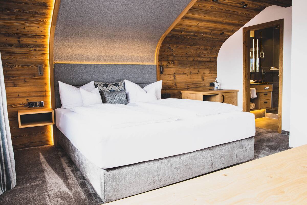Une chambre moderne avec un grand lit, des murs en bois et une armoire intégrée.