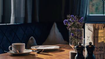 A table with a cup, saucer, plate, and cutlery, a vase with flowers, and a menu.