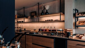 A modern kitchen with wooden cabinets, a built-in oven, and a variety of kitchenware and utensils. - Hotel Alpenkönig (Oberstaufen)