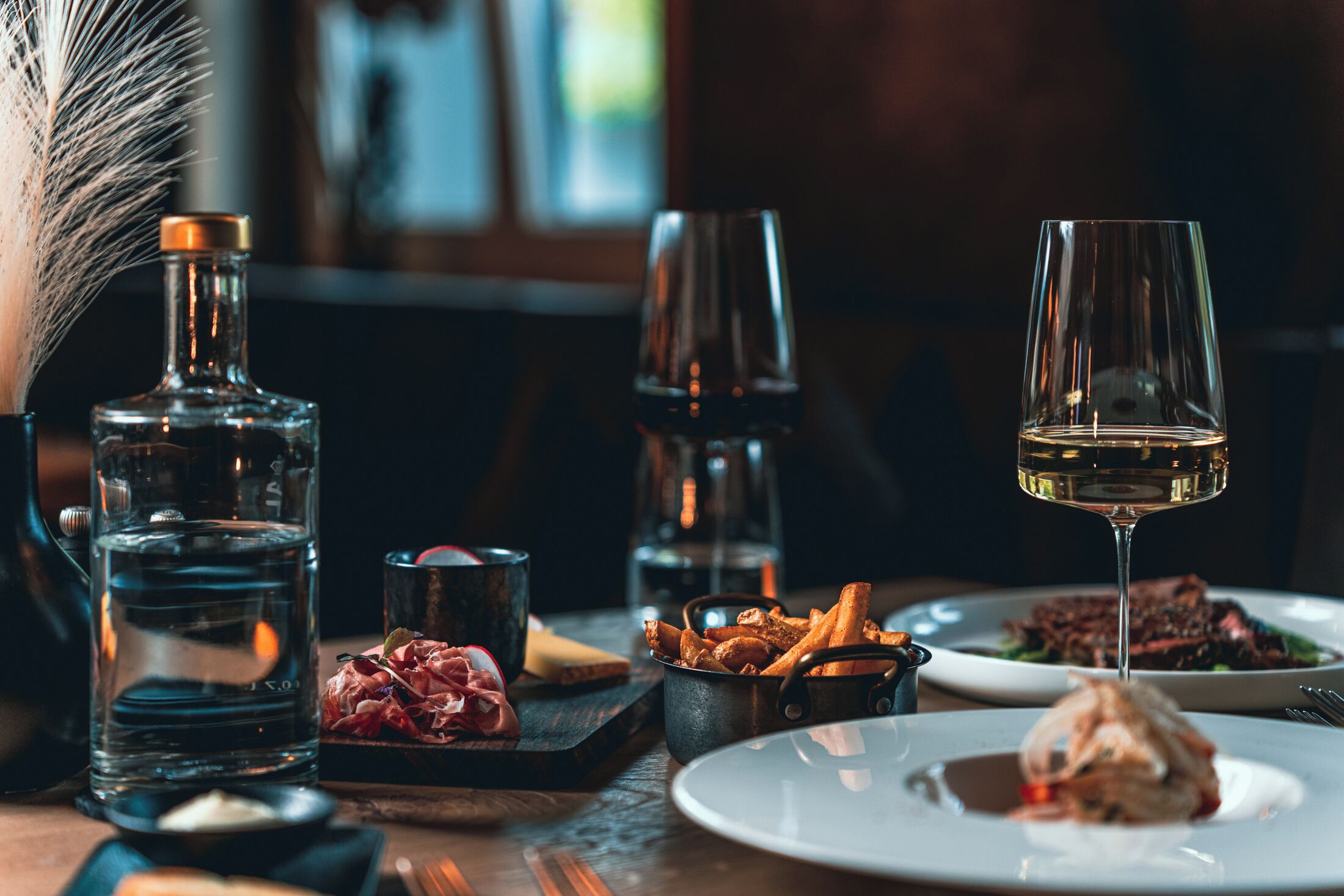 A dining table with various dishes, a bottle of water, and glasses of wine.