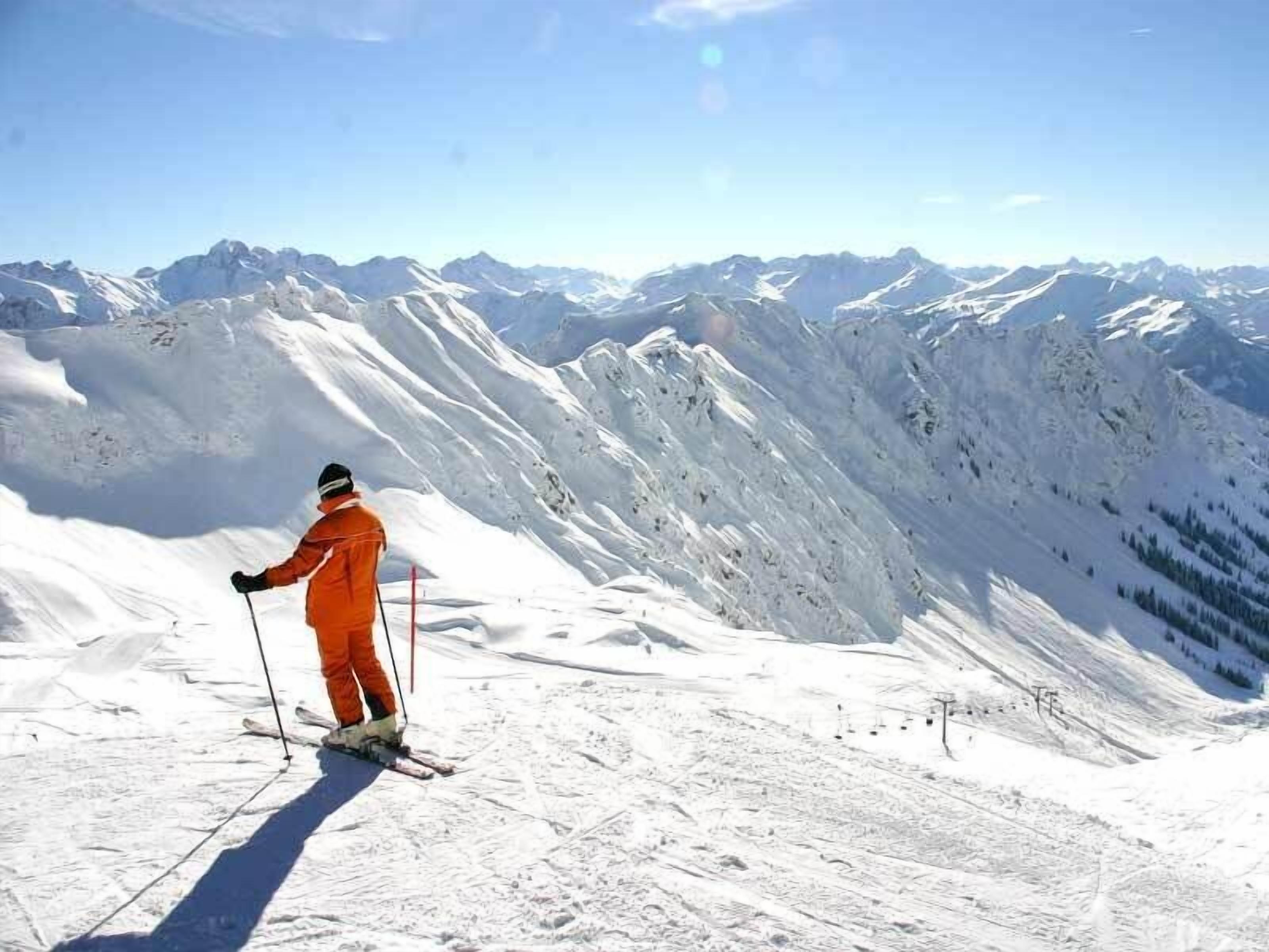 A person skiing on a snowy mountain slope with a clear view of distant mountains.