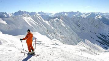A person skiing on a snowy mountain slope with a clear view of distant mountains.