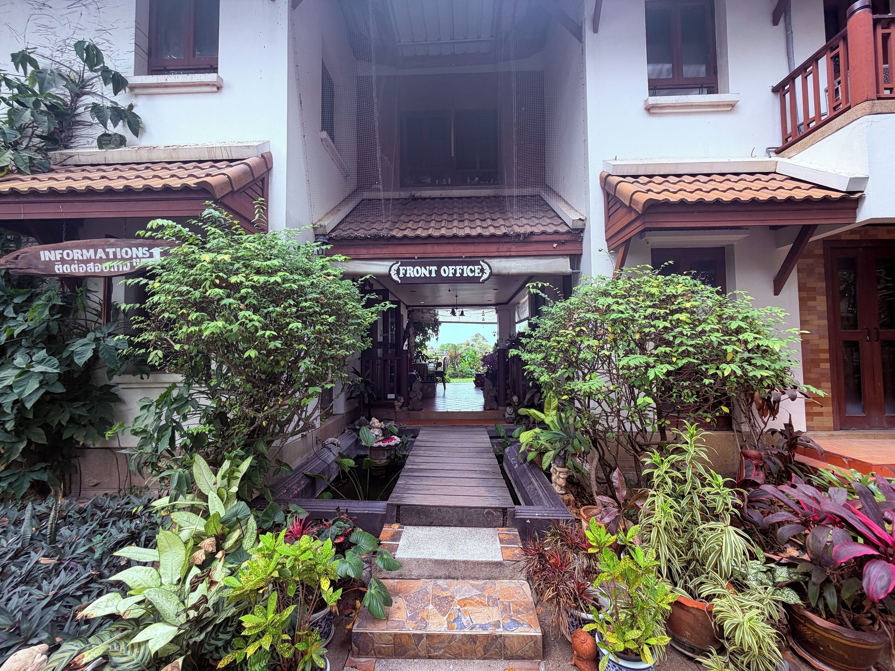 A building with a front office, a covered walkway, and various potted plants.