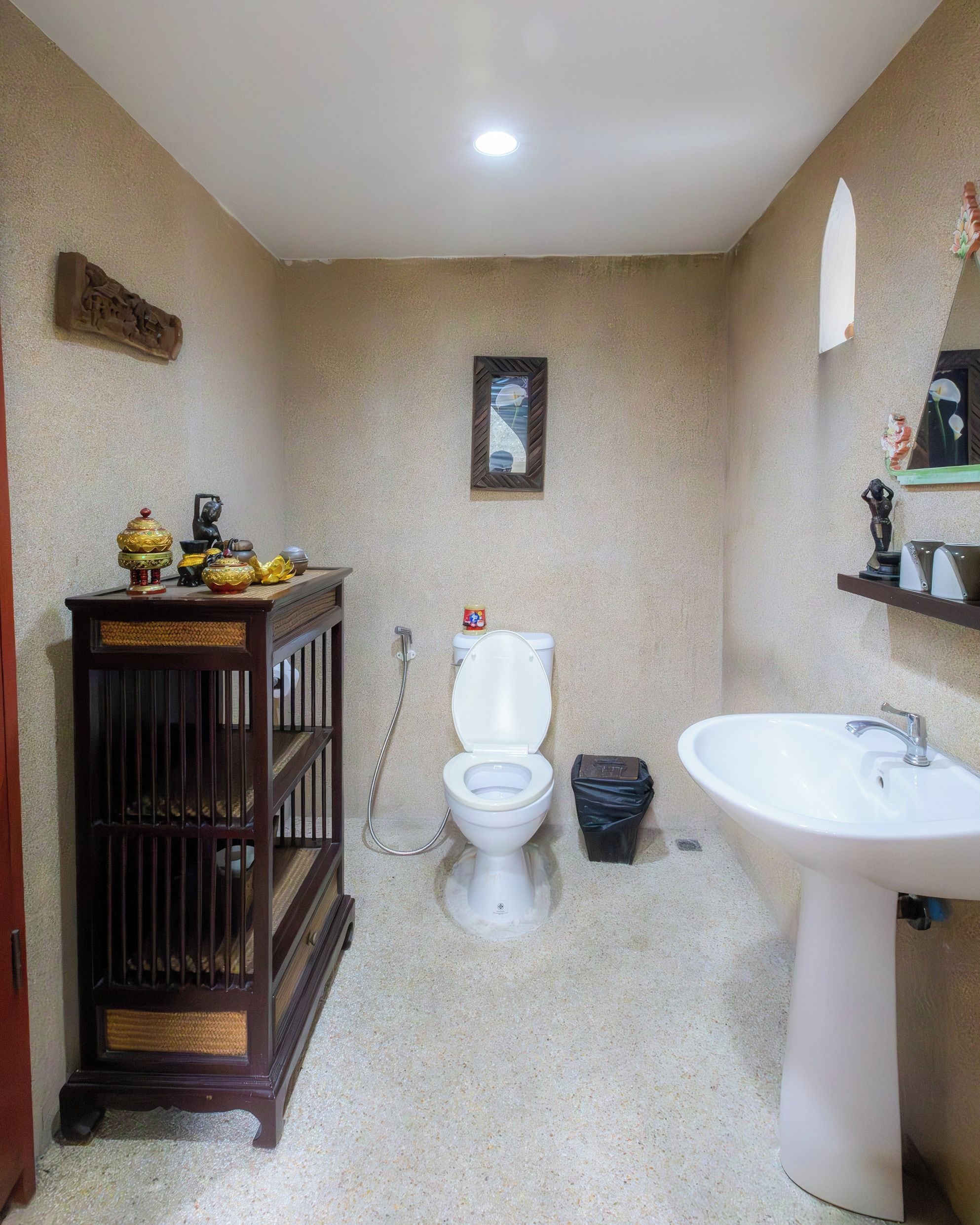 A bathroom with a toilet, sink, and a wooden cabinet with decorative items.