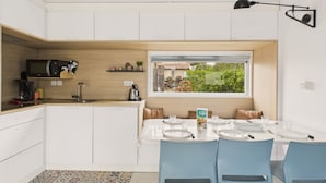 A compact kitchen with a built-in microwave, a coffee maker, and a window overlooking a garden. - Nice chalet in a residence in St Hilaire (Saint-Hilaire-de-Riez)