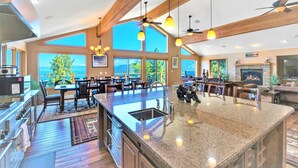 Una cocina amplia con una isla grande, vigas de madera y ventanas que ofrecen vistas al exterior.