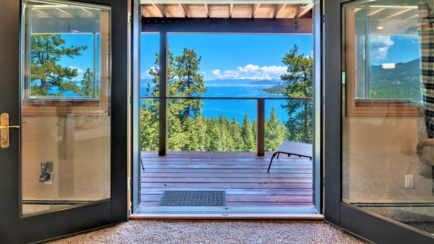 Una habitación moderna con un amplio ventanal que da a un balcón y vistas al mar y a las montañas.