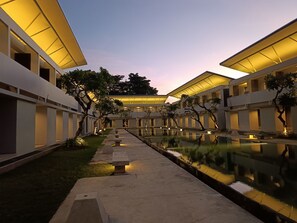 Un bâtiment moderne doté d’une cour intérieure et d’un bassin dont la surface reflète la lumière.