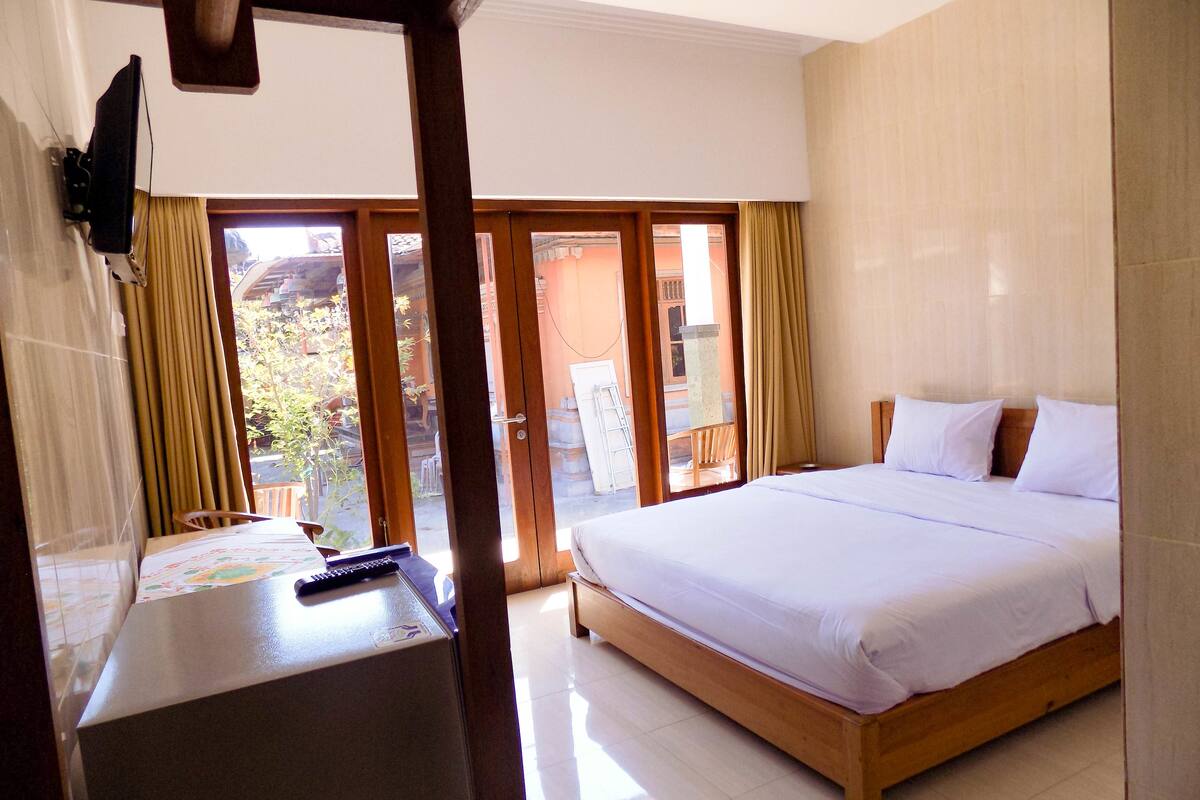 A hotel room with a large bed, a desk with a computer, and a view of the outside.