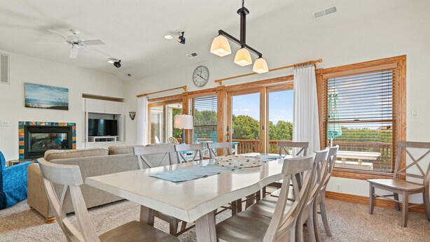 A spacious living area with a dining table, chairs, a sofa, a television, and large windows offering a view of the outdoors. - Sea-U-Later!: 820 Ft to Beach Access; Private Pool, Hot Tub (Duck)