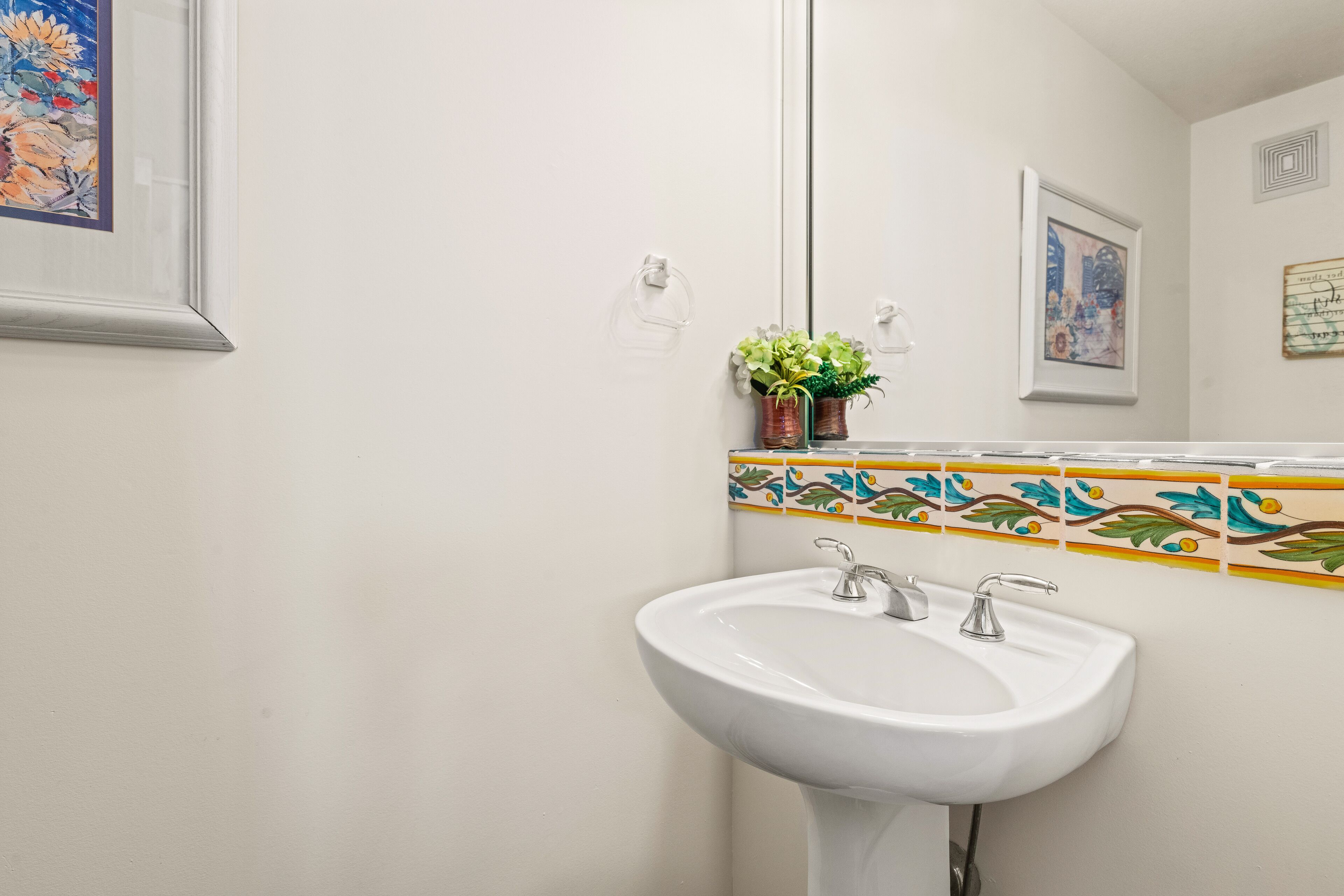 Un baño con lavamanos blanco, un espejo y salpicadero de azulejos.