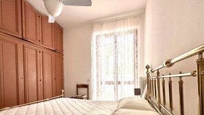 Ein Schlafzimmer mit Bett, Holzschrank und einem Fenster mit Vorhängen.
