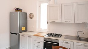 Eine Küche mit weißen Schränken, einem Edelstahl-Kühlschrank, einem Gasherd und einer Holz Arbeitsplatte.