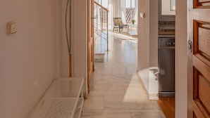 A hallway with a bench, an archway, and a kitchen area visible through the doorway.