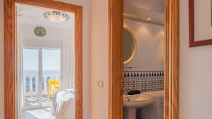 A hotel corridor with a bed, a bathroom, and a view of the sea.