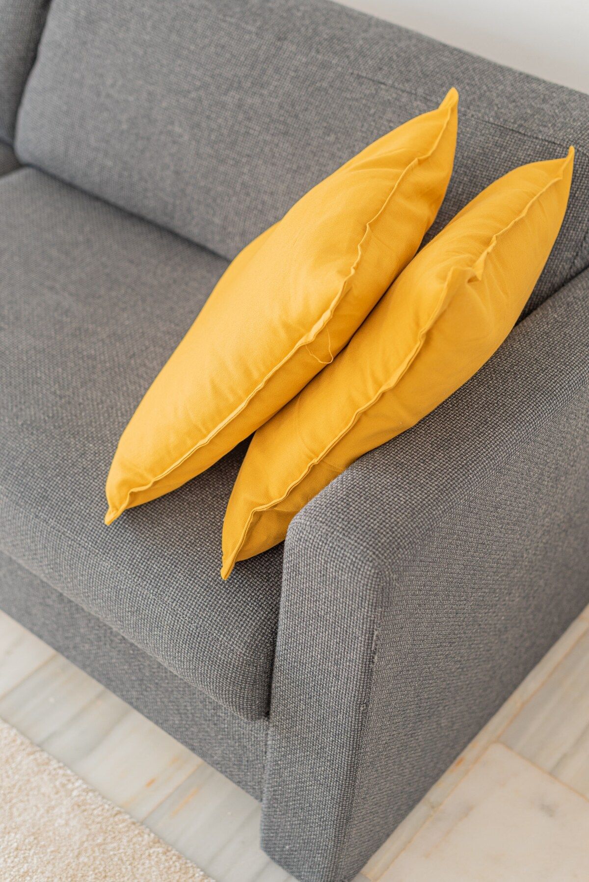 Un sofá gris con dos almohadas amarillas.