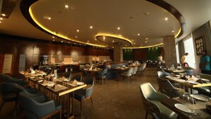 Un restaurant spacieux au design moderne, doté d’un bar central et de nombreuses tables et chaises.