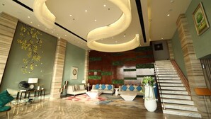 Un hall d’entrée moderne avec un luminaire au plafond aux lignes courbes, un escalier et un espace détente comprenant des canapés et une table basse.