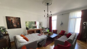 Ett modernt vardagsrum med en säng, en soffa, stolar, en öppen spis och en tv.
