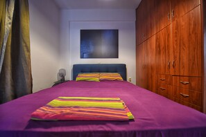 Un dormitorio con cama, armario y un cuadro en la pared.