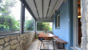 Une terrasse couverte avec un mur en pierre, une table en bois et un banc.