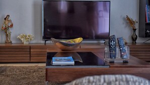 Un salon équipé d’un téléviseur à écran plat, d’une table basse avec un magazine et d’un support pour la télécommande.