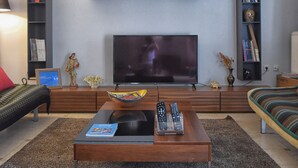Un salon moderne doté d’un téléviseur à écran plat, d’une table basse en bois et de bibliothèques.