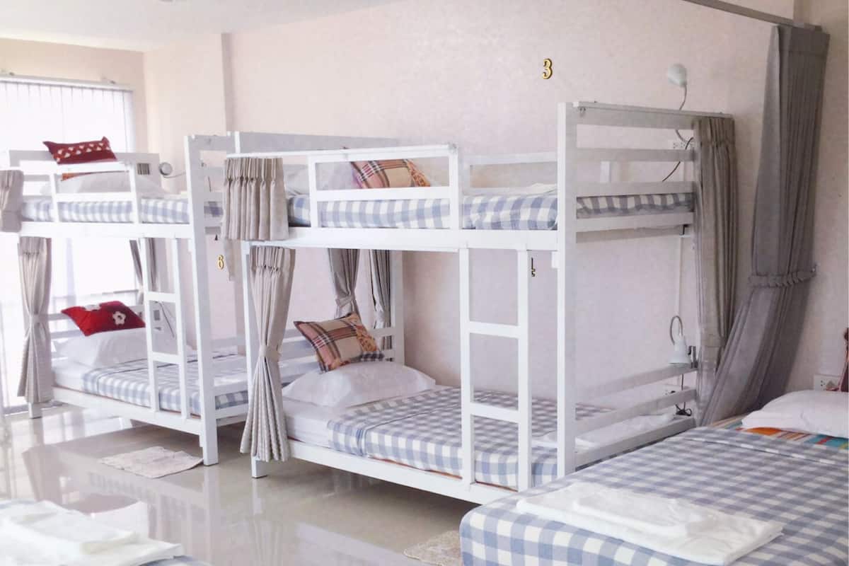 A room with bunk beds, each with a checkered bedspread and pillows.