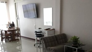 A modern living room with a sofa, a coffee table, and a TV mounted on the wall. - Chogun Hostel (Chumphon)