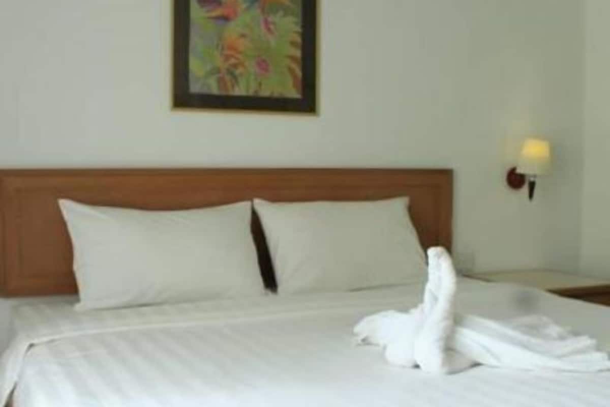 Een hotelkamer met een net opgemaakt bed, een schilderij aan de muur en een wandlamp.
