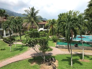 A resort with a swimming pool, palm trees, and a mountain backdrop.